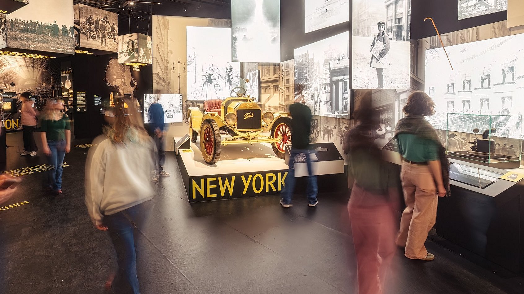 Besucherinnen und Besucher erkunden den hell beleuchteten Ausstellungsraum mit historischen Objekten zur Titanic.