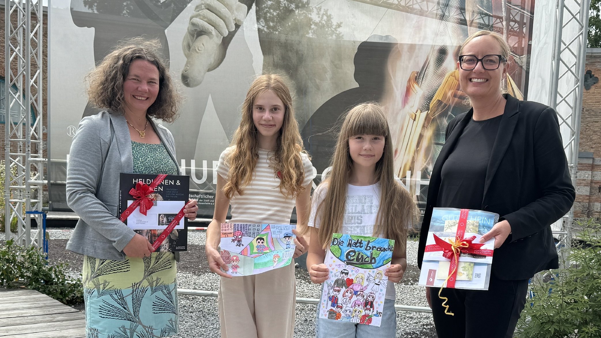 Vier Personen stehen auf dem Vorplatz des Ausstelungszentrums Lokschuppen: Leiterin des Lokschuppens Dr. Jennifer Morscheiser, Sonderpreisgewinnerin Silvia Baier, Gewinnerin des Hauptpreises Luisa Baier, OVB-Chefredakteurin Rosi Gantner 