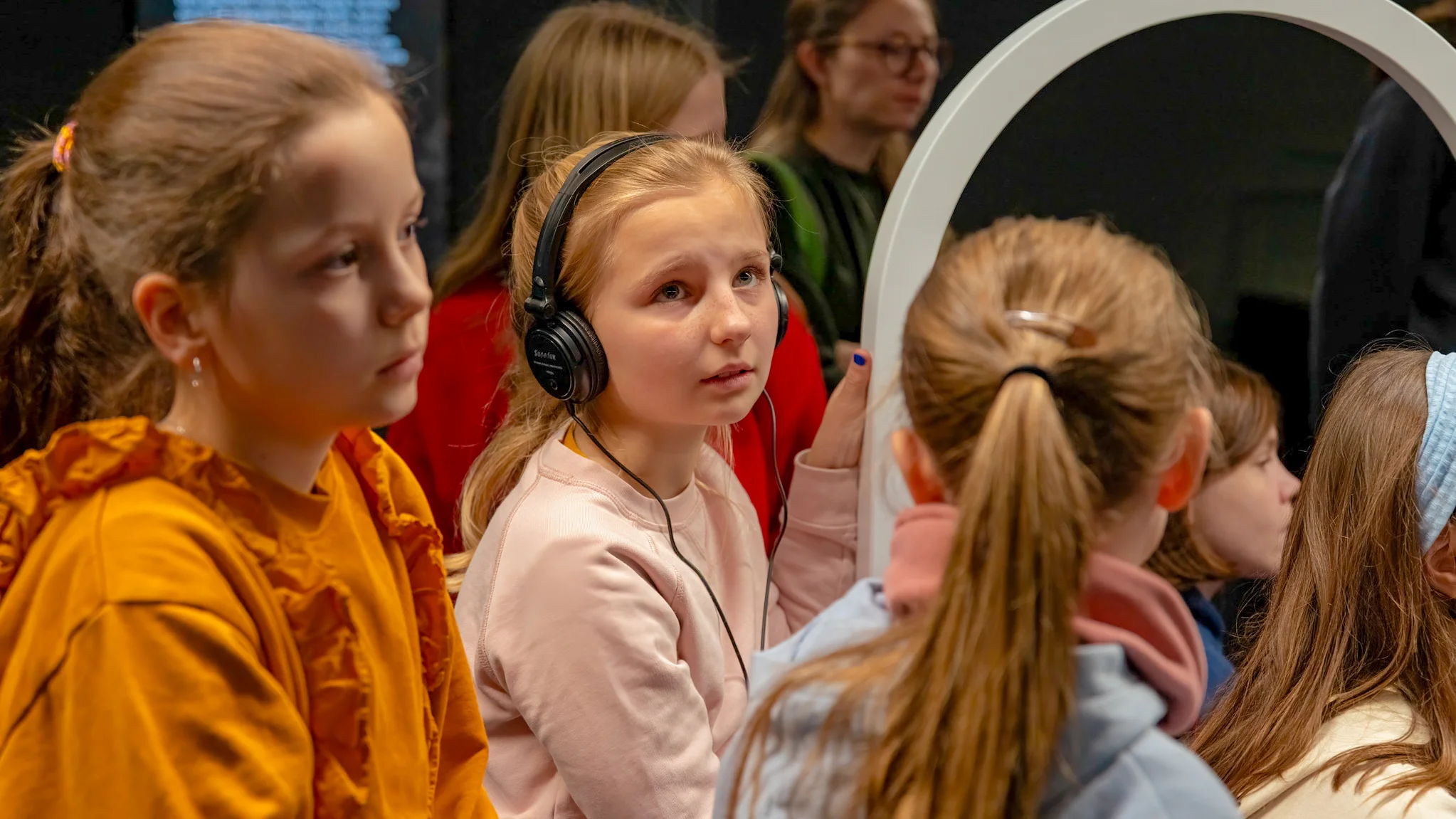 Kinder betrachten interaktive Station in der Römer-Ausstellung im Lokschuppen Rosenheim mit Kopfhörern.