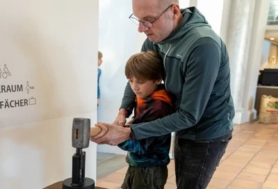 Junge mit Papa Münze prägen Lokschuppen Rosenheim Ausstellung Römer 2026 Copyright Axel Jusseit