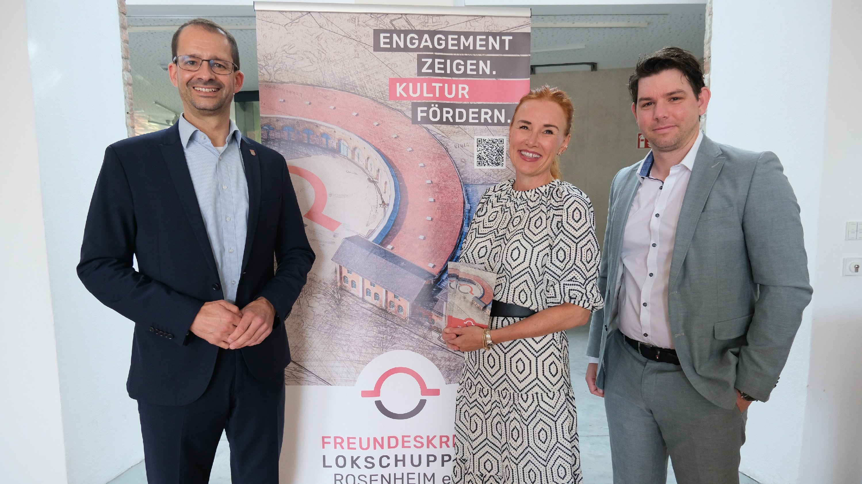 Rosenheims Oberbürgermeister Andreas März und Geschäftsführer der  Veranstaltungs- und Kongress GmbH Rosenheim Florian Englert begrüßen Cornelia  Hartinger, Vorständin der Hartinger Heimatstiftung im Ausstellungszentrum  Lokschuppen Rosenheim.