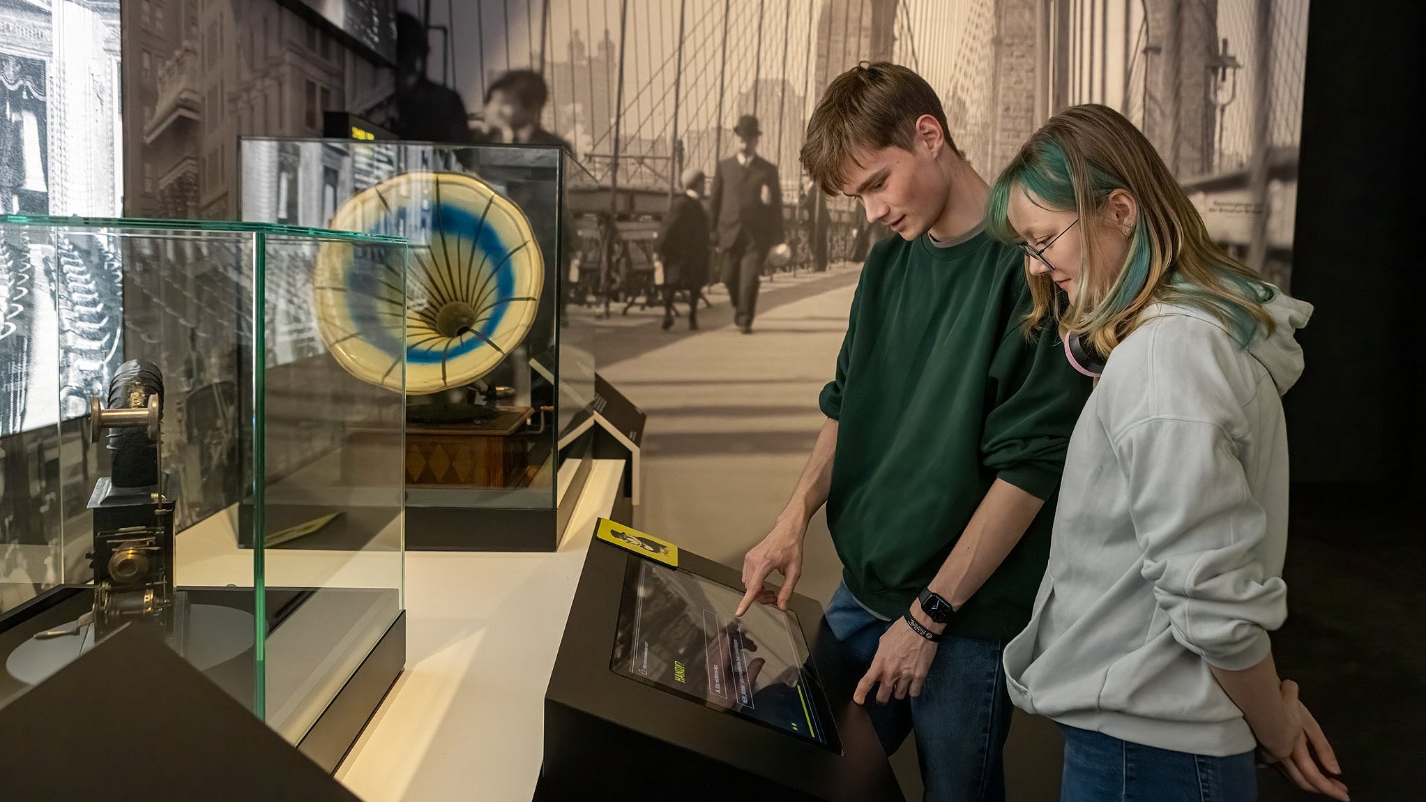 Zwei Personen nehmen an einem interaktiven Erfindungsquiz in der Titanic-Ausstellung teil.