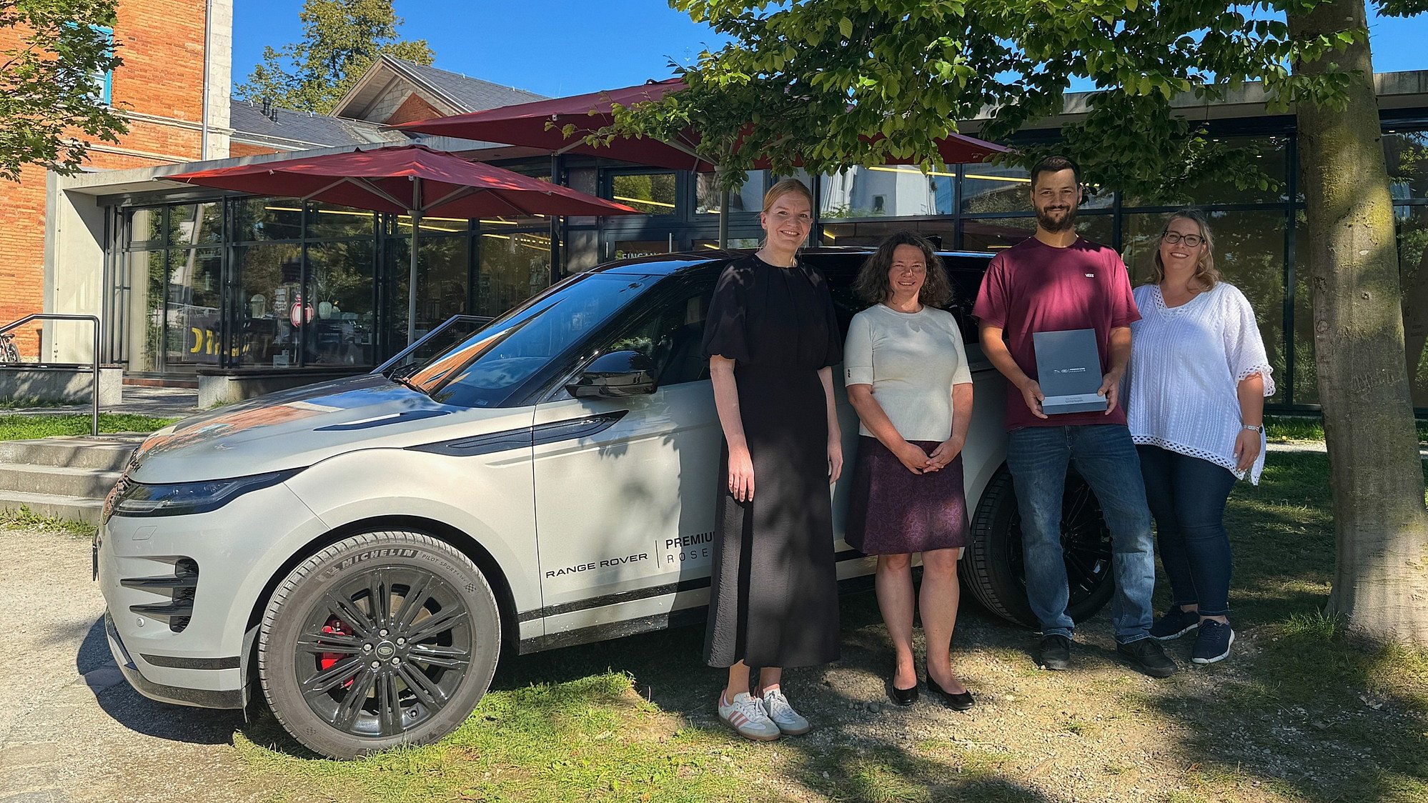 Vier Personen stehen vor einem grauen Range Rover Evoque, Preisübergabe des OVB-Preisrätsels zur Titanic-Ausstellung.
